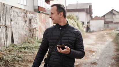 Ein Mann der mit einem Smartphone in der Hand auf der Straße steht